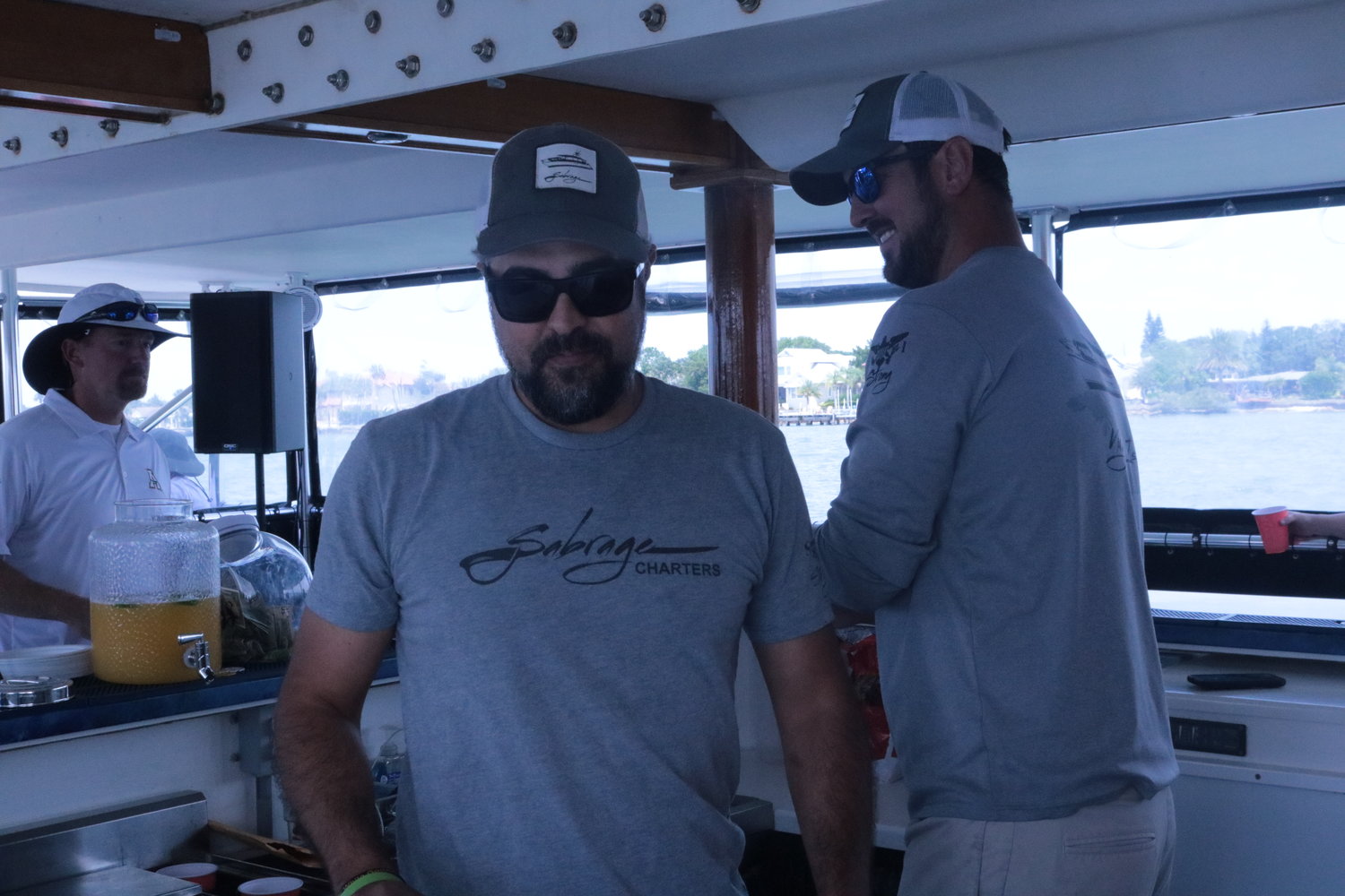 Ian Bartlett (right) and Jon Cordero, of Sabrage Charters, serve guests at the Sister Hazel Booze Cruise last Sunday.